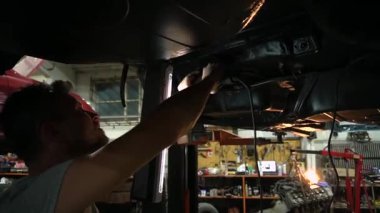 Özel egzoz sistemi ve egzoz manifoldu araba genç tamirci tamir ve eski gri bir araba monte bir trafik kazası sonra arka süspansiyon yeni sessiz bloklar baskı arka süspansiyon onarım ve yeni fren diskleri yükleme