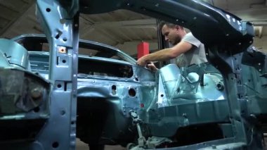 Özel egzoz sistemi ve egzoz manifoldu araba genç tamirci tamir ve eski gri bir araba monte bir trafik kazası sonra arka süspansiyon yeni sessiz bloklar baskı arka süspansiyon onarım ve yeni fren diskleri yükleme