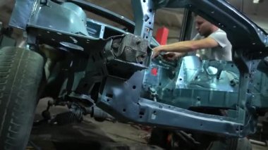 Özel egzoz sistemi ve egzoz manifoldu araba genç tamirci tamir ve eski gri bir araba monte bir trafik kazası sonra arka süspansiyon yeni sessiz bloklar baskı arka süspansiyon onarım ve yeni fren diskleri yükleme