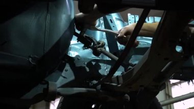 Özel egzoz sistemi ve egzoz manifoldu araba genç tamirci tamir ve eski gri bir araba monte bir trafik kazası sonra arka süspansiyon yeni sessiz bloklar baskı arka süspansiyon onarım ve yeni fren diskleri yükleme