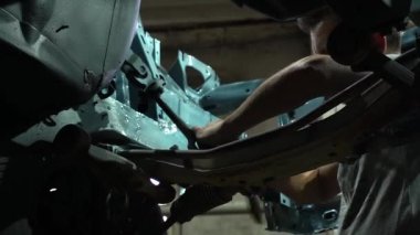 Özel egzoz sistemi ve egzoz manifoldu araba genç tamirci tamir ve eski gri bir araba monte bir trafik kazası sonra arka süspansiyon yeni sessiz bloklar baskı arka süspansiyon onarım ve yeni fren diskleri yükleme