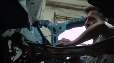 Özel egzoz sistemi ve egzoz manifoldu araba genç tamirci tamir ve eski gri bir araba monte bir trafik kazası sonra arka süspansiyon yeni sessiz bloklar baskı arka süspansiyon onarım ve yeni fren diskleri yükleme