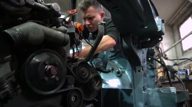 Özel egzoz sistemi ve egzoz manifoldu araba genç tamirci tamir ve eski gri bir araba monte bir trafik kazası sonra arka süspansiyon yeni sessiz bloklar baskı arka süspansiyon onarım ve yeni fren diskleri yükleme