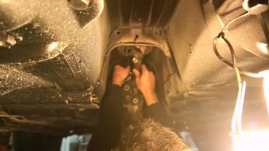 Özel egzoz sistemi ve egzoz manifoldu araba genç tamirci tamir ve eski gri bir araba monte bir trafik kazası sonra arka süspansiyon yeni sessiz bloklar baskı arka süspansiyon onarım ve yeni fren diskleri yükleme