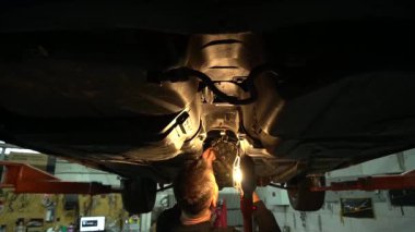 Özel egzoz sistemi ve egzoz manifoldu araba genç tamirci tamir ve eski gri bir araba monte bir trafik kazası sonra arka süspansiyon yeni sessiz bloklar baskı arka süspansiyon onarım ve yeni fren diskleri yükleme