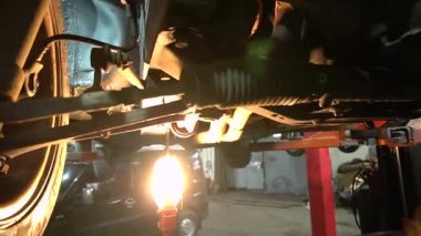 Özel egzoz sistemi ve egzoz manifoldu araba genç tamirci tamir ve eski gri bir araba monte bir trafik kazası sonra arka süspansiyon yeni sessiz bloklar baskı arka süspansiyon onarım ve yeni fren diskleri yükleme