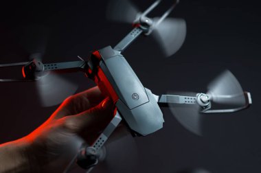 Karanlık bir odada bir insanın elindeki kırmızı ışıkla aydınlatılan bir kuadkopter uçma ve fırlatma simülasyonu