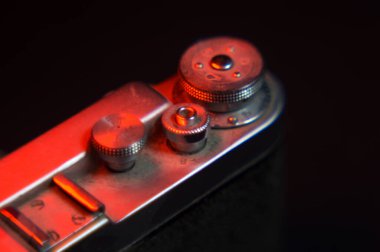 Eski bir film kamerası. Kırmızı ışıkla aydınlatılmış. Eski bir mercekle çekilmiş.