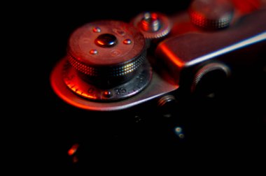 Eski bir film kamerası. Kırmızı ışıkla aydınlatılmış. Eski bir mercekle çekilmiş.