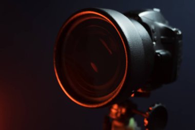 Kırmızı ışıkta, özel filtresi olan bir stüdyoda tripoda siyah SLR kamera kullanıldı.