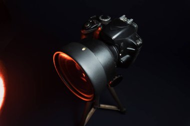 Kırmızı ışıkta, özel filtresi olan bir stüdyoda tripoda siyah SLR kamera kullanıldı.