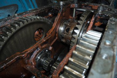 Eski bir garajda eski bir mavi traktörün tamiri, bir vites kutusunun sökülmesi ve montajı,