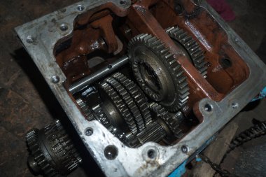 Eski bir garajda eski bir mavi traktörün tamiri, bir vites kutusunun sökülmesi ve montajı,