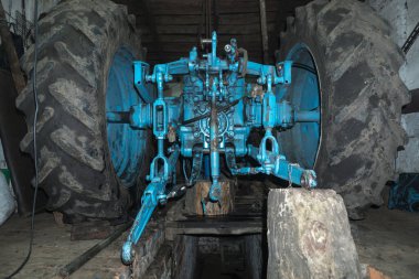 Eski bir garajda eski bir mavi traktörün tamiri, bir vites kutusunun sökülmesi ve montajı,
