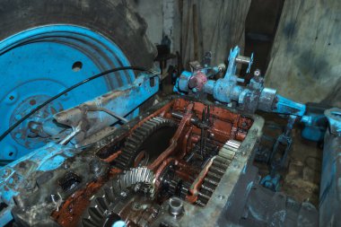 Eski bir garajda eski bir mavi traktörün tamiri, bir vites kutusunun sökülmesi ve montajı,