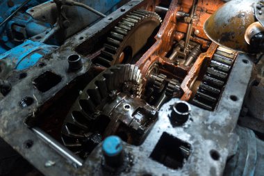 Eski bir garajda eski bir mavi traktörün tamiri, bir vites kutusunun sökülmesi ve montajı,