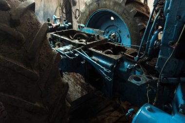 Eski bir garajda eski bir mavi traktörün tamiri, bir vites kutusunun sökülmesi ve montajı,