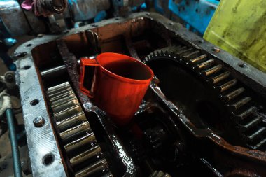 Eski bir garajda eski bir mavi traktörün tamiri, bir vites kutusunun sökülmesi ve montajı,