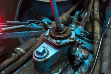 Eski bir garajda eski bir mavi traktörün tamiri, bir vites kutusunun sökülmesi ve montajı,