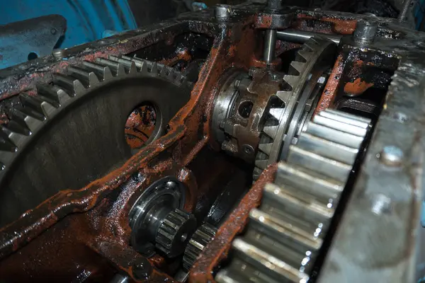 Eski bir garajda eski bir mavi traktörün tamiri, bir vites kutusunun sökülmesi ve montajı,