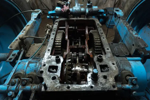 Eski bir garajda eski bir mavi traktörün tamiri, bir vites kutusunun sökülmesi ve montajı,