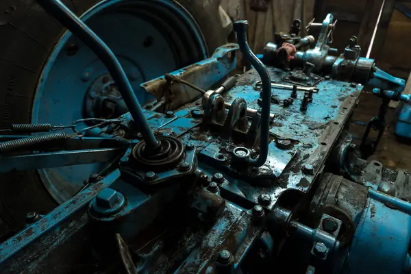 Eski bir garajda eski bir mavi traktörün tamiri, bir vites kutusunun sökülmesi ve montajı,