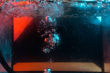 Su dokusu gürleyen kaos içinde hava kabarcıkları yaratıyor mavi ve kırmızı ışıkta dışarı kaçıyorlar.