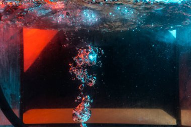 Su dokusu gürleyen kaos içinde hava kabarcıkları yaratıyor mavi ve kırmızı ışıkta dışarı kaçıyorlar.