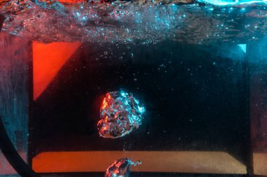 Su dokusu gürleyen kaos içinde hava kabarcıkları yaratıyor mavi ve kırmızı ışıkta dışarı kaçıyorlar.