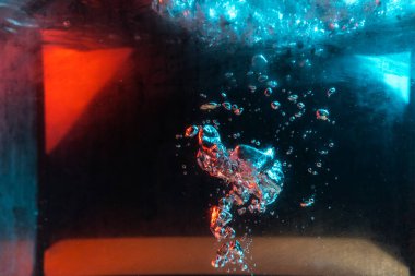 Su dokusu gürleyen kaos içinde hava kabarcıkları yaratıyor mavi ve kırmızı ışıkta dışarı kaçıyorlar.