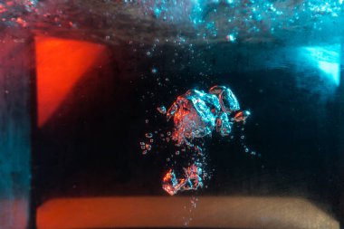 Su dokusu gürleyen kaos içinde hava kabarcıkları yaratıyor mavi ve kırmızı ışıkta dışarı kaçıyorlar.