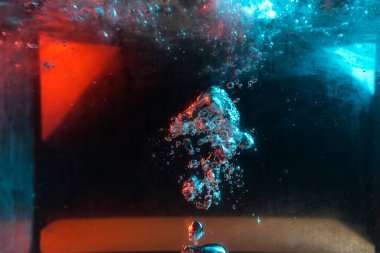 Su dokusu gürleyen kaos içinde hava kabarcıkları yaratıyor mavi ve kırmızı ışıkta dışarı kaçıyorlar.