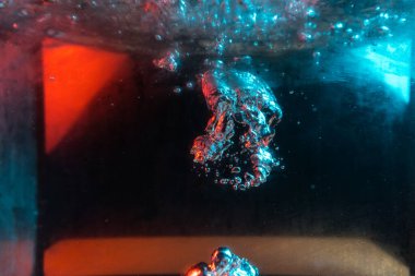 Su dokusu gürleyen kaos içinde hava kabarcıkları yaratıyor mavi ve kırmızı ışıkta dışarı kaçıyorlar.