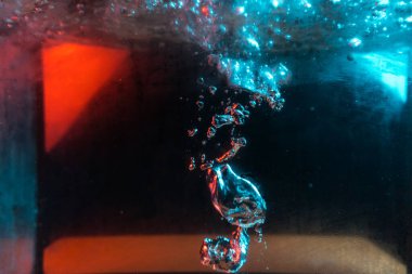 Su dokusu gürleyen kaos içinde hava kabarcıkları yaratıyor mavi ve kırmızı ışıkta dışarı kaçıyorlar.