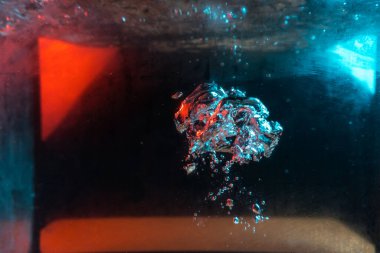 Su dokusu gürleyen kaos içinde hava kabarcıkları yaratıyor mavi ve kırmızı ışıkta dışarı kaçıyorlar.