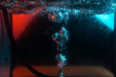 Su dokusu gürleyen kaos içinde hava kabarcıkları yaratıyor mavi ve kırmızı ışıkta dışarı kaçıyorlar.