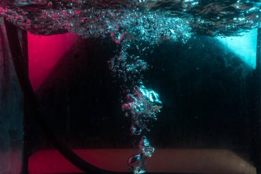 Su dokusu gürleyen kaos içinde hava kabarcıkları yaratıyor mavi ve kırmızı ışıkta dışarı kaçıyorlar.