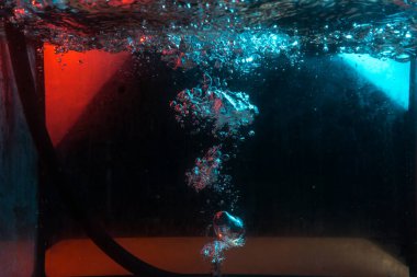 Su dokusu gürleyen kaos içinde hava kabarcıkları yaratıyor mavi ve kırmızı ışıkta dışarı kaçıyorlar.