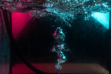 Su dokusu gürleyen kaos içinde hava kabarcıkları yaratıyor mavi ve kırmızı ışıkta dışarı kaçıyorlar.