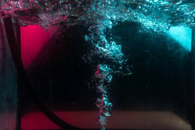 Su dokusu gürleyen kaos içinde hava kabarcıkları yaratıyor mavi ve kırmızı ışıkta dışarı kaçıyorlar.