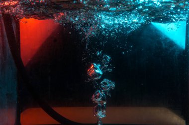 Su dokusu gürleyen kaos içinde hava kabarcıkları yaratıyor mavi ve kırmızı ışıkta dışarı kaçıyorlar.