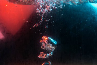 Su dokusu gürleyen kaos içinde hava kabarcıkları yaratıyor mavi ve kırmızı ışıkta dışarı kaçıyorlar.