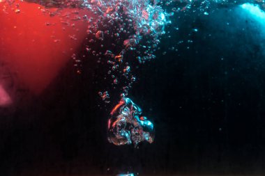 Su dokusu gürleyen kaos içinde hava kabarcıkları yaratıyor mavi ve kırmızı ışıkta dışarı kaçıyorlar.