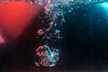 Su dokusu gürleyen kaos içinde hava kabarcıkları yaratıyor mavi ve kırmızı ışıkta dışarı kaçıyorlar.