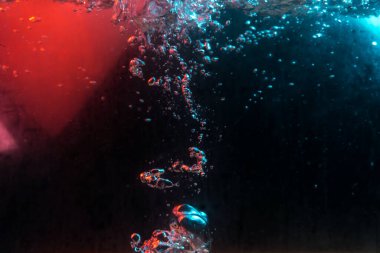 Su dokusu gürleyen kaos içinde hava kabarcıkları yaratıyor mavi ve kırmızı ışıkta dışarı kaçıyorlar.