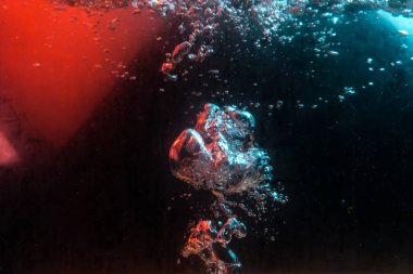 Su dokusu gürleyen kaos içinde hava kabarcıkları yaratıyor mavi ve kırmızı ışıkta dışarı kaçıyorlar.