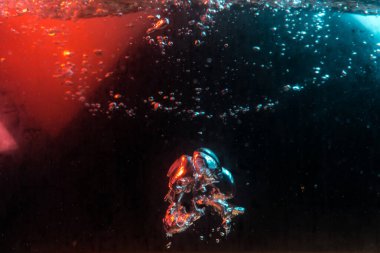 Su dokusu gürleyen kaos içinde hava kabarcıkları yaratıyor mavi ve kırmızı ışıkta dışarı kaçıyorlar.