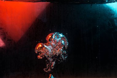 Su dokusu gürleyen kaos içinde hava kabarcıkları yaratıyor mavi ve kırmızı ışıkta dışarı kaçıyorlar.