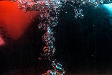 Su dokusu gürleyen kaos içinde hava kabarcıkları yaratıyor mavi ve kırmızı ışıkta dışarı kaçıyorlar.