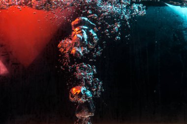 Su dokusu gürleyen kaos içinde hava kabarcıkları yaratıyor mavi ve kırmızı ışıkta dışarı kaçıyorlar.